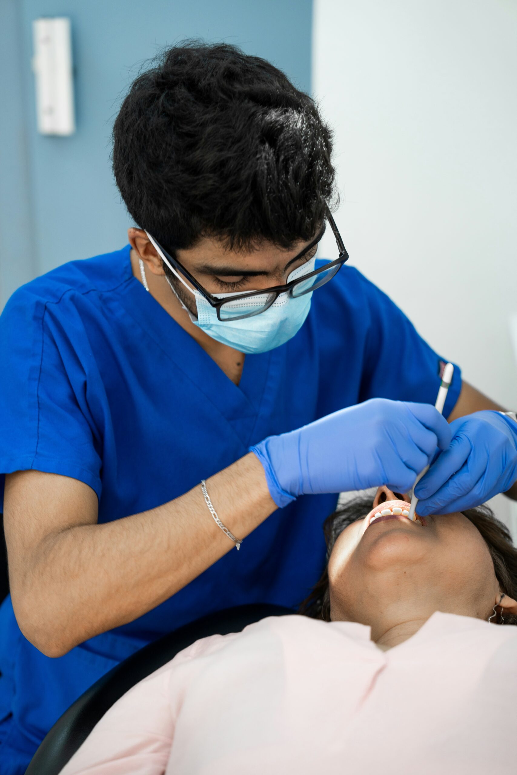 a man in a blue shirt is getting his teeth checked